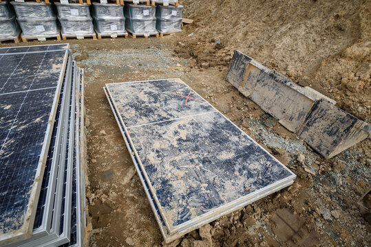 Stacked solar modules with a red crossed-out symbol indicating they are damaged. Concept of damage from inappropriate delivery standards.