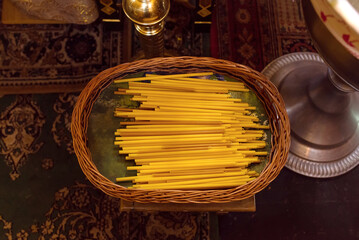 Set of stack of yellow church candles in a basket in the church