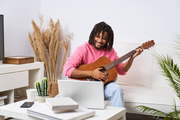 A man in a pink shirt is playing a guitar in a living room