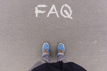 FAQ, frequently asked questions, text on asphalt ground, feet and shoes on floor