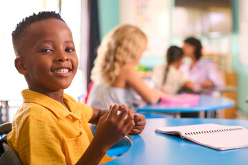 Portrait Of Male Primary Or Elementary School Student At Desk In Multi-Cultural Class 