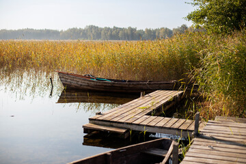pier for boats on an autumn lake, early autumn, rest and relaxation in the first autumn days, blue...
