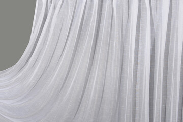 Obraz premium The white tulle curtain hangs in folds. The waves of the fabric are transparent and clean.