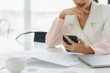 Businesswoman using apps on cell phones, reading news, fast connection in meeting room.