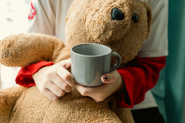 Teenage Girl from Generation Z Enjoying Hot Drink by Window with Teddy Bear Close-Up