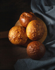 Baked buns. Freshly baked bread rolls on a cutting board with linen tablecloth. 