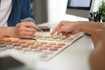 Closeup client choosing colors in swatches palette for apartment renovation