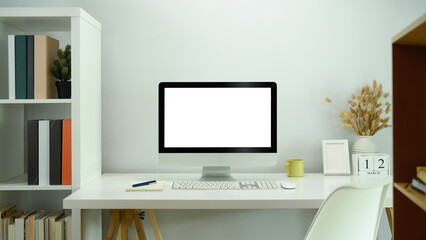 Front view computer display with blank white screen on white table in comfortable home