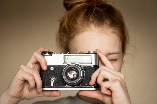 Film retro camera in the beautiful hands of young red-haired girl