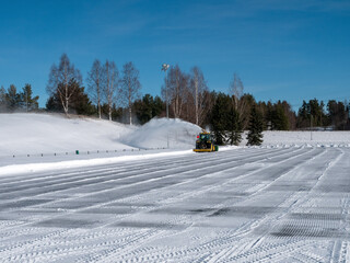 Tractor with snowblower blowing snow on a sports area, Kempele Finland