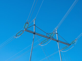 high voltage power lines with metallic pylons on blue sky