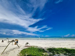 Fototapeten Zanzibar beach with wooden sailboat under blue sky Sun © TravelLensPro