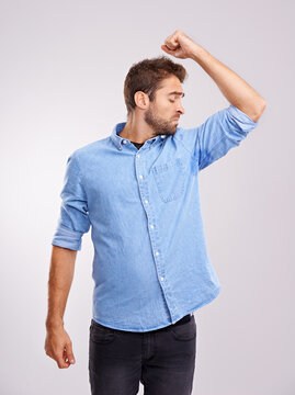 Man, smelling armpit and sweat stain, bad hygiene or body odor with stink isolated on white background. Hyperhidrosis, poor hygiene and dirty, foul or negative with disgust for underarm in studio
