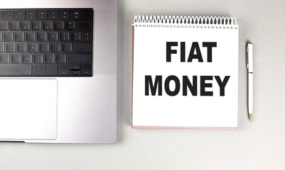 FIAT MONEY text on notebook with laptop and pen