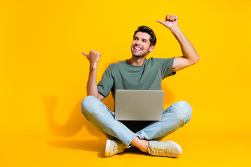 Full length photo of dreamy positive guy wear khaki t-shirt working modern gadget two thumbs empty space isolated yellow color background