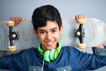 Portrait, happy and boy with skateboard, headphones and recreation with music and cheerful. Kid, face or childhood with skater or headset with joy or hobby with smile, casual or gen z with confidence © Tasneem/peopleimages.com