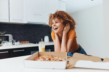 Smiling African American woman enjoying delicious pizza in the comfort of her home kitchen