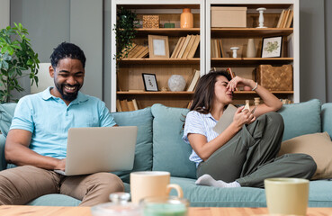 Simple living. Young couple man and woman at home working on laptop, reading book, talking and...