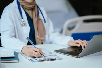 Doctor sitting at table and writing on a document report in hospital office. Medical healthcare staff and doctor service.