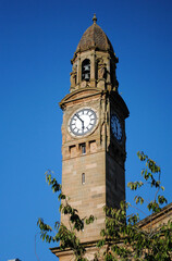 Victorian Stone Clock Tower with Cupola seen against Blue Sky
