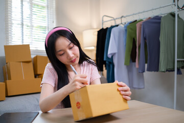 Young start up online business SME beautiful woman female Asian working writing on box for prepare shipping product to customer, Shipping shopping online, SMW working with box at home