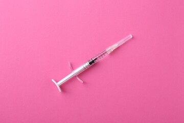 Injection cosmetology. One medical syringe on pink background, top view