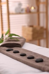 Towel with arranged spa stones on massage table in recreational center