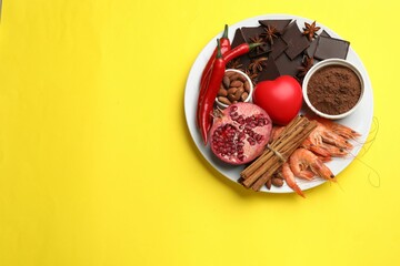 Natural aphrodisiac. Different products and heart model on yellow background, top view