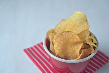 Potato chips in red bowl with red napkin isolated on white.