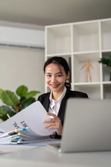 Young business woman asian or employee accounting bookkeeping documents checking financial data or marketing report working in office with laptop. Paperwork management