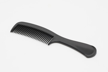 A black plastic comb on a white background.