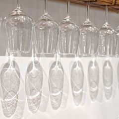 crystal wine glasses hanging on stemware hanger with shadow reflection on white wall