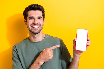 Photo of intelligent pleasant man dressed khaki t-shirt directing at smartphone display empty space...