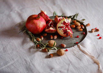 Image of Still Life with Turkish Pomegranate and olive branch on old retro plate. Dark wood...