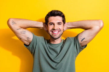 Portrait of toothy beaming satisfied guy with stubble wear stylish t-shirt arm behind head chill...