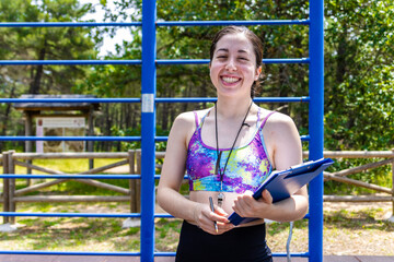 Smiling athlete with clipboard at outdoor workout area