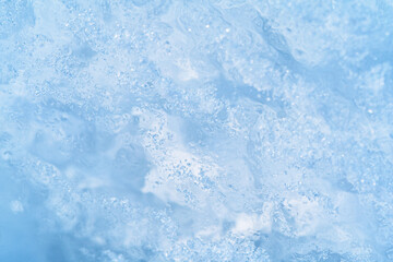 Close-up photo of transparent light blue ice of Baikal lake with white frost ornament. Great...