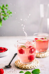 Sommer Getränk mit Himbeeren in zwei Gläser auf einem grauen Tisch. Spritzig, Erfrischung.