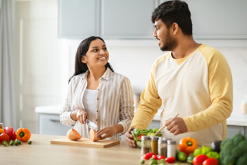 Indian Spouses Having Conversation While Preparing Food In Cozy Kitchen