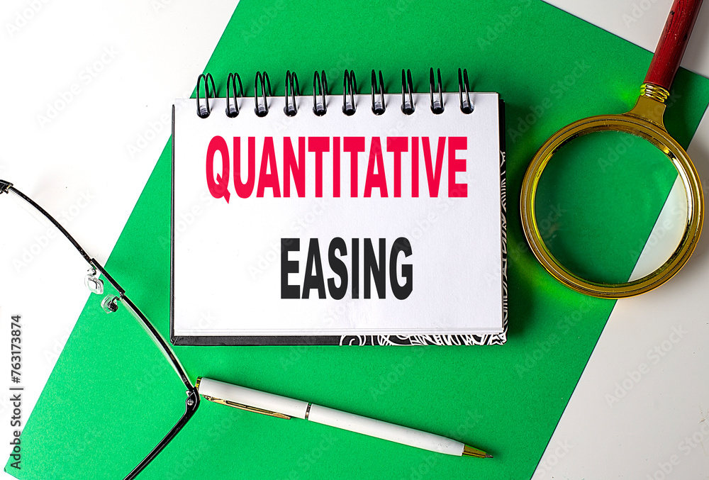 Aufkleber quantitative easing text on notebook on green paper