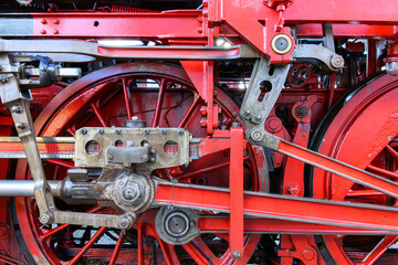 Two red wheels of an old steam locomotive with drive linkage - 763175434