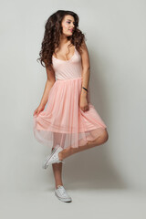 Studio portrait of brunette woman in fashionable summer dress posing on white background