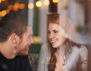 Naklejka premium Couple, happiness and love on date at cafe for bonding, romance and healthy relationship with relax. Man, woman and affection at coffee shop with smile, trust and window on anniversary vacation