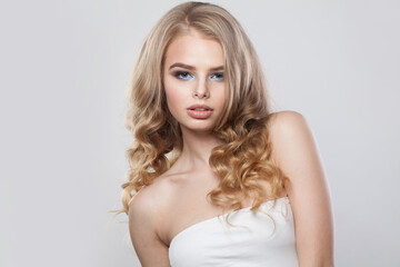 Obraz na płótnie Canvas Beautiful young fashion woman with healthy blonde hair and make-up on white background