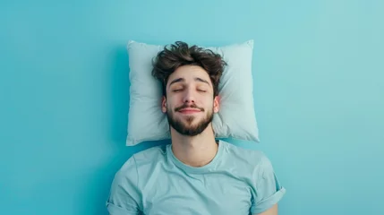 Fotobehang a young man sleeping on pillow isolated on pastel blue colored background Sleep deeply peacefully rest. Top above high angle view photo portrait of satisfied .senior wear blue  shirt © Sittipol 