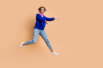 Fototapeta na wymiar Full size portrait of astonished nice girl jump raise opened arms catch empty space isolated on beige color background