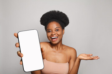 Perfect healthy woman holding smartphone with white empty blank screen display on gray studio wall background. Happy model with phone - 763179269