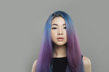 Cute young asian woman with long blue and purple hairstyle on gray background, fashion beauty portrait - 763179423