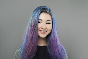 Young Happy Asian woman with colorful colored blue and purple hair on gray background, portrait - 763179451