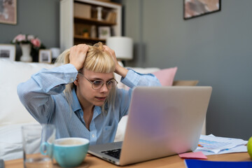 Computer bug. Young nervous frustrated freelance woman in home office having trouble with laptop or...